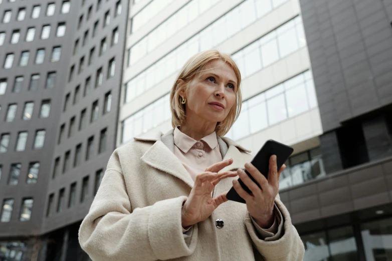 a woman in a beige jacket looking at soing on her hand