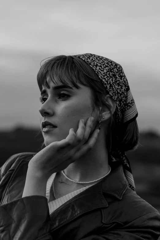 a woman in leather jacket posing with her hand on her ear