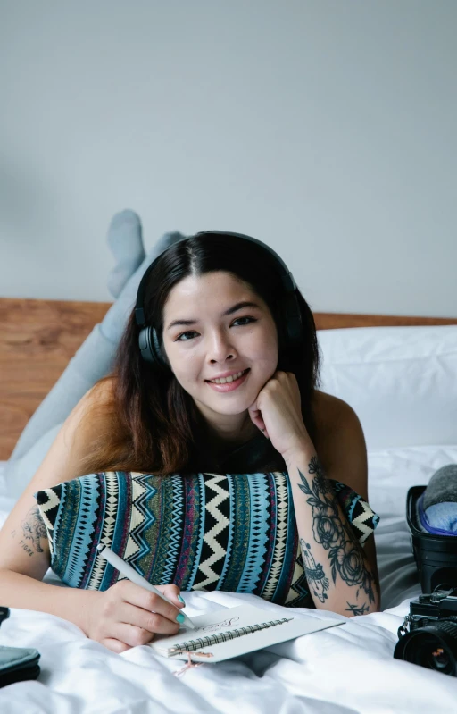 a smiling woman in headphones laying on a bed