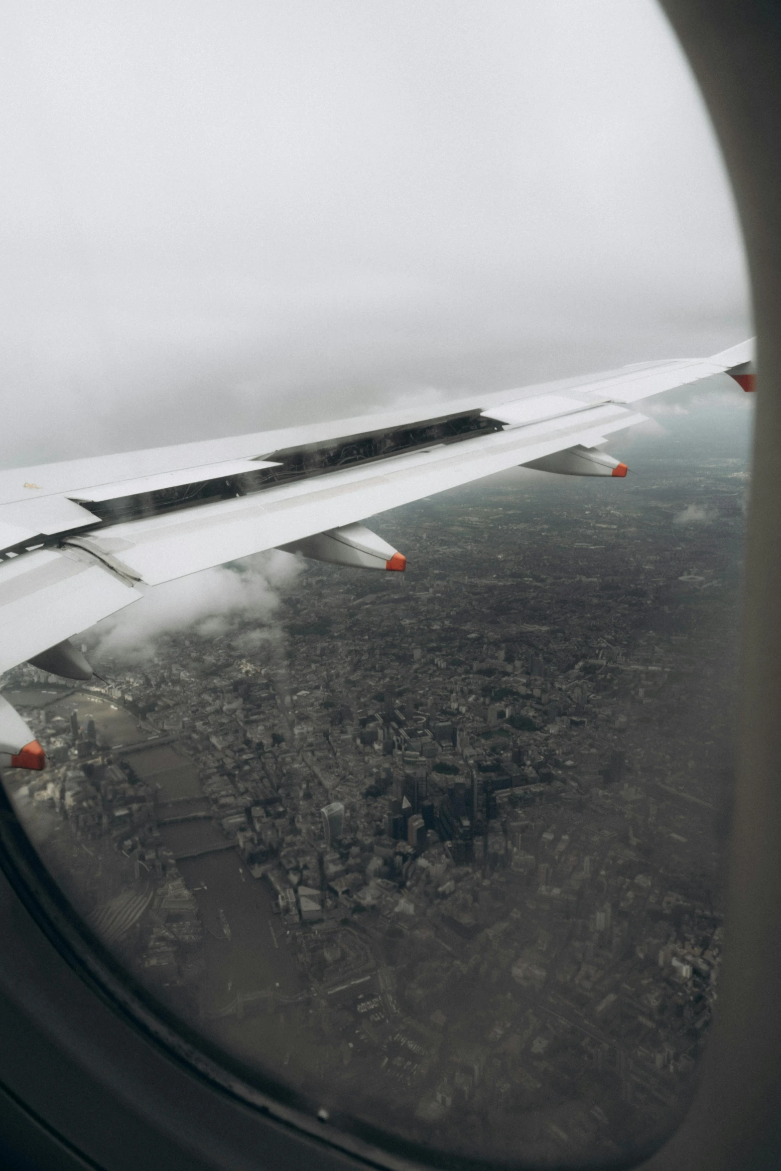 airplane window showing a landscape and some clouds