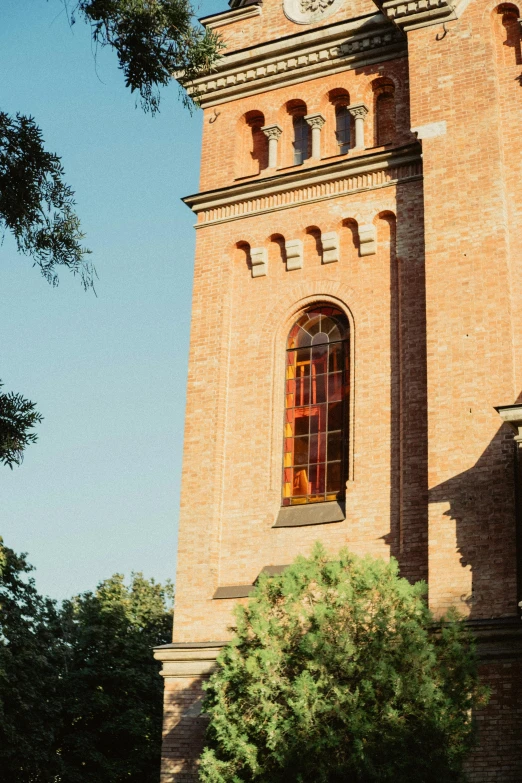 a tower clock sits among greenery and a blue sky