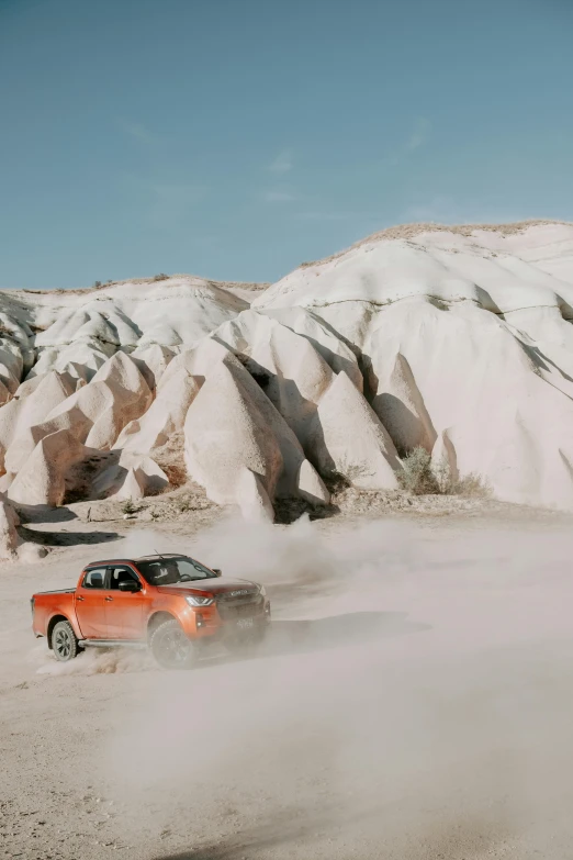 an orange car driving through the sand in a desert