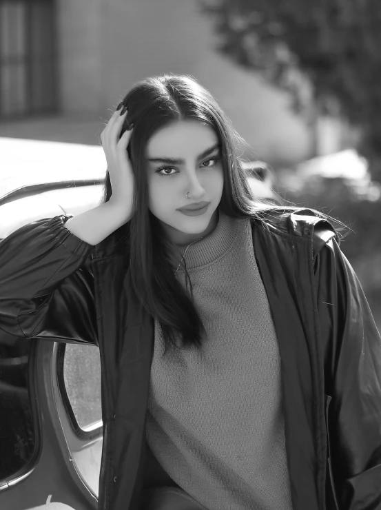 a woman poses with her hair down and wears a coat