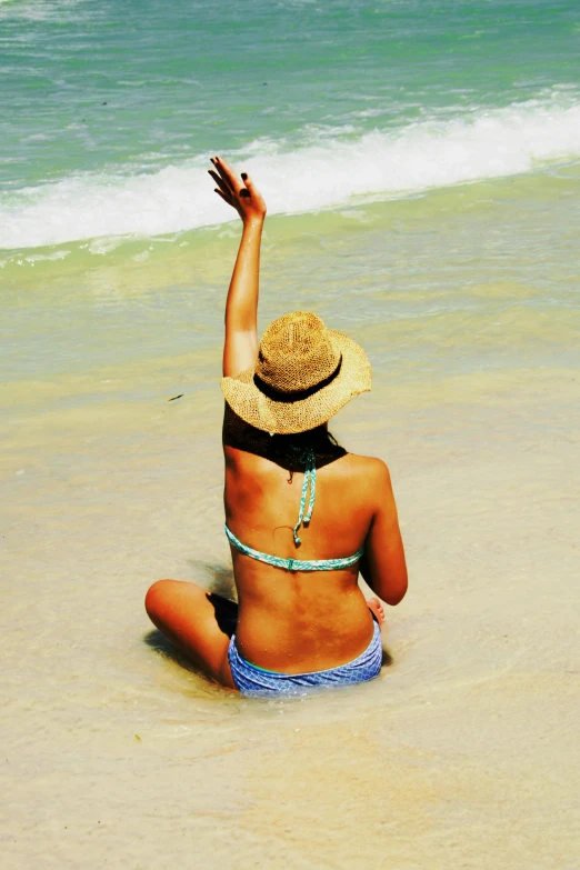 the girl is sitting on the beach looking out at the water