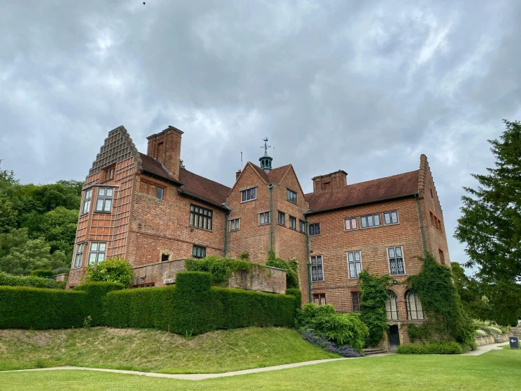 a big brick building with many windows and trimmed hedges