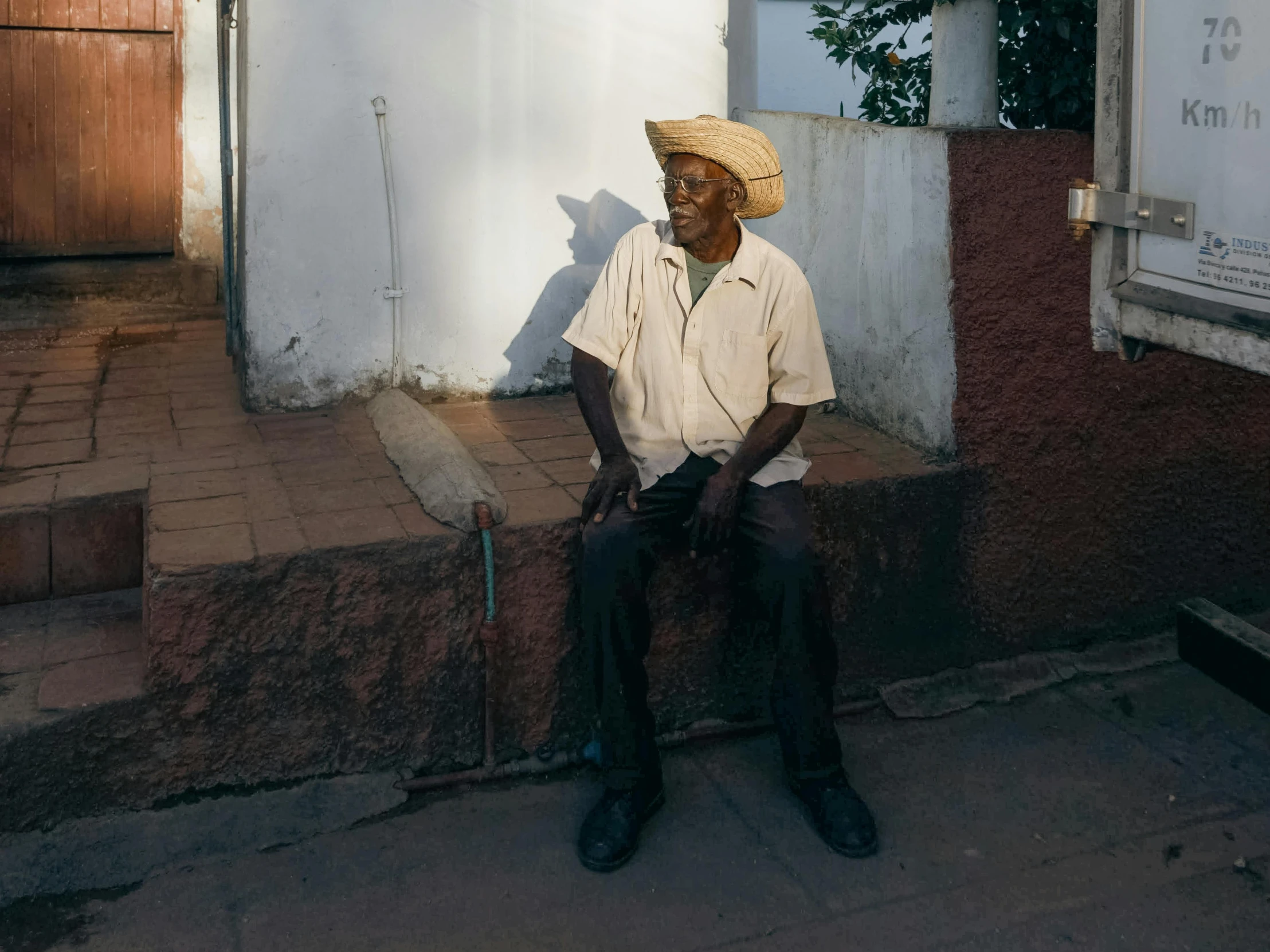 a man is sitting outside of his house on the sidewalk