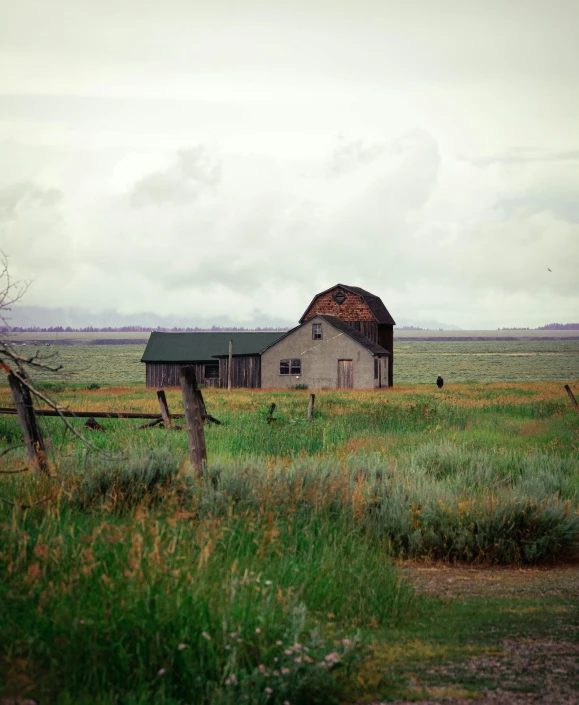 old barn in a field under cloudy skies