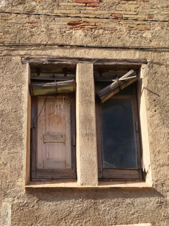 two windows with wooden trim, and peeling paint