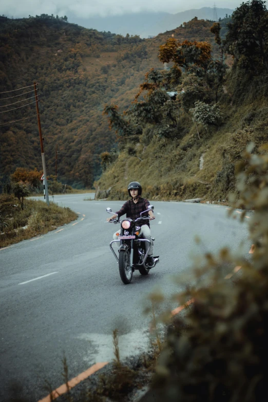 motorcycle driver riding down a road surrounded by mountains