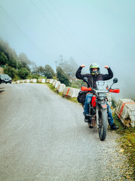 man sitting on motorcycle on winding road in countryside