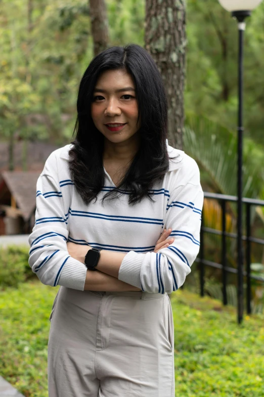 asian business woman with long black hair and crossed arms standing in park