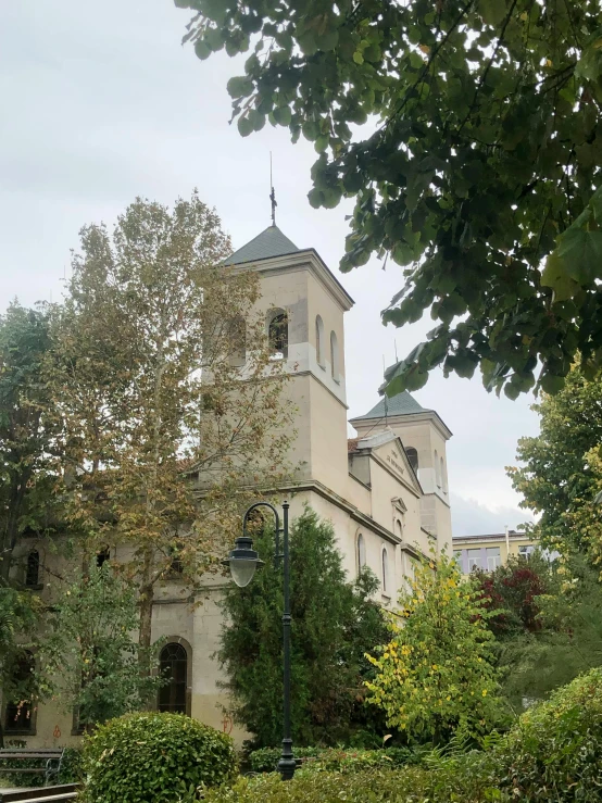 a church on a hill behind green bushes