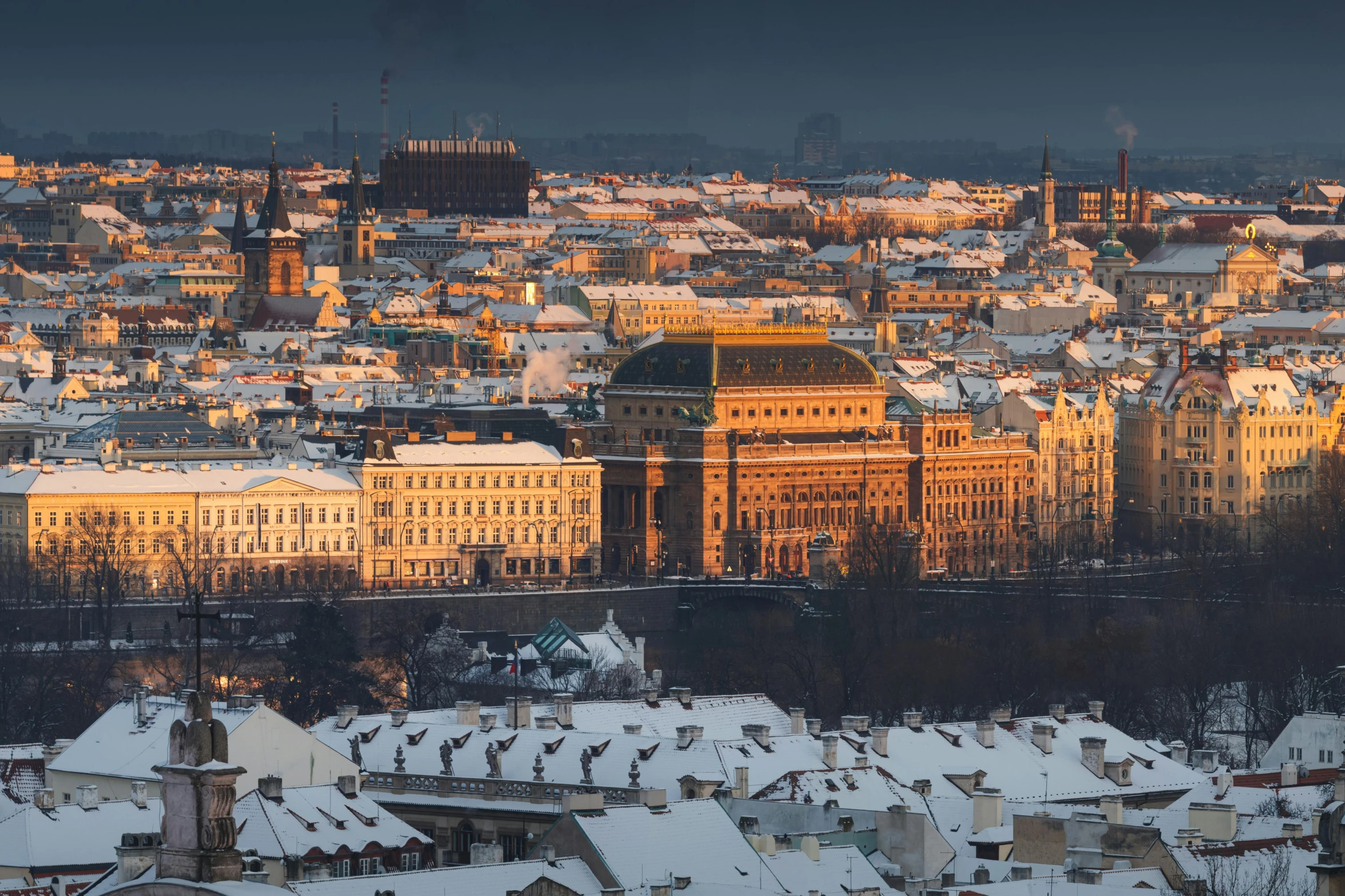 the cityscape shows several large buildings with some white roofs and snow on them