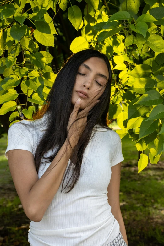 a girl is hiding her face behind some leaves