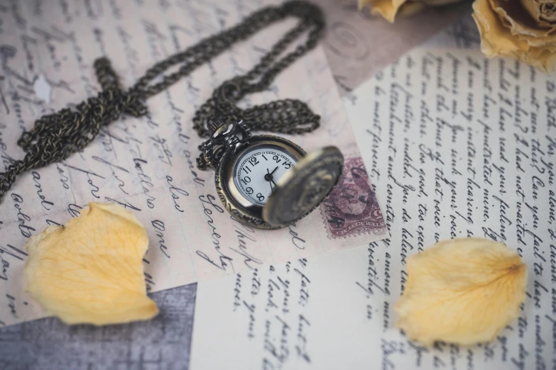 a pocket watch is on top of an old piece of paper