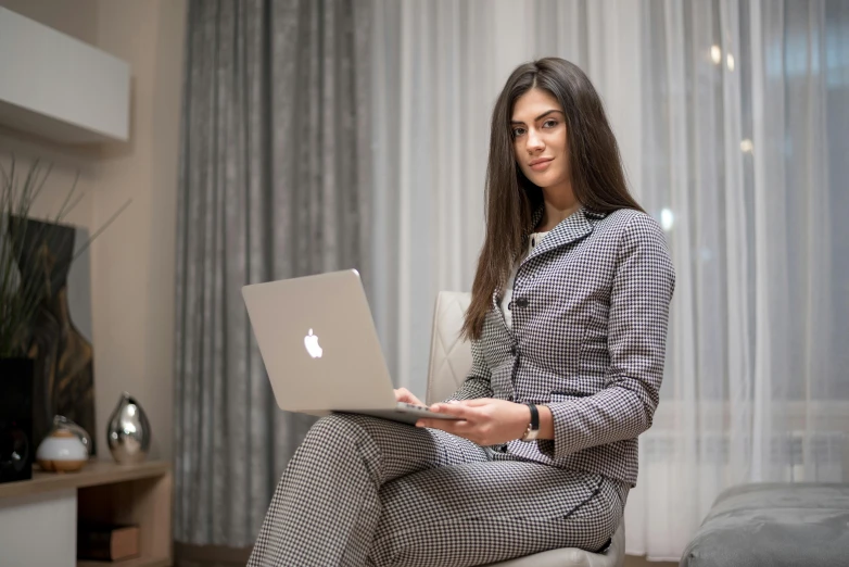 a pretty young lady sitting on a chair using her laptop