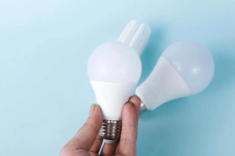 a pair of white light bulb holders being held by hand