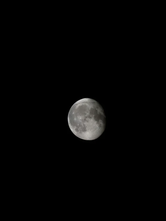 the full moon rising above the dark black sky