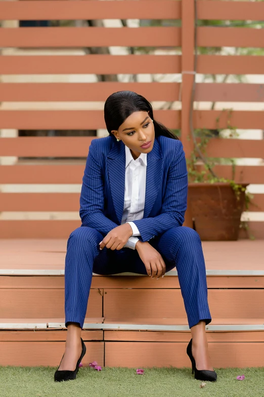 a woman is sitting on some steps in a blue suit