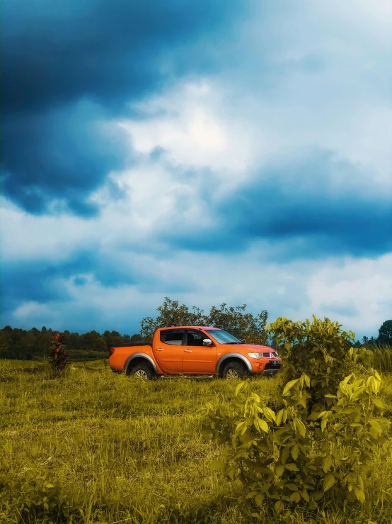 an orange car driving through a field during the day