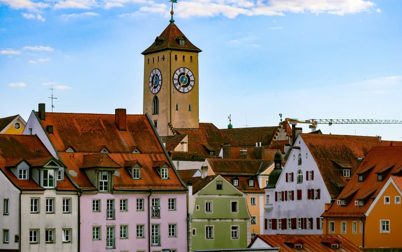 a view of several different colored houses with a clock tower