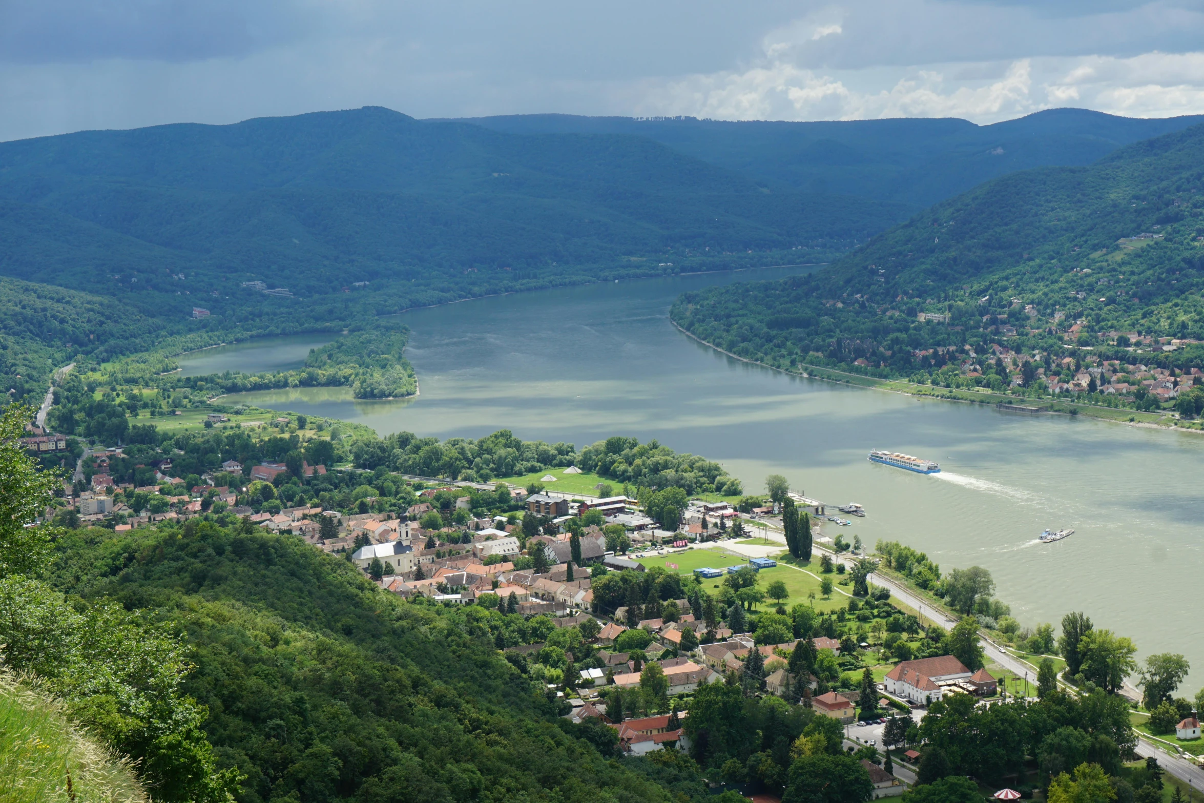 the mountains are full of green trees and some buildings