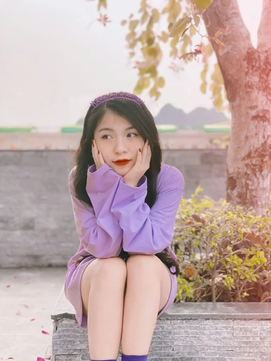 an asian  is sitting on a bench in purple and smiling