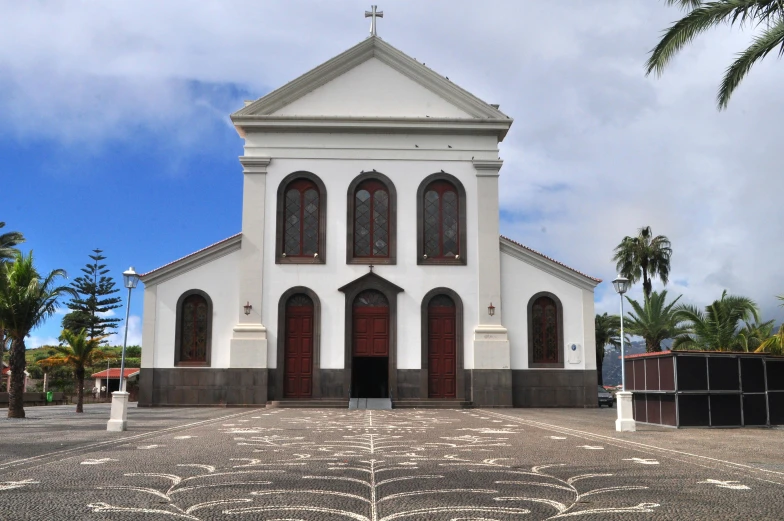 a church with two windows surrounded by palm trees