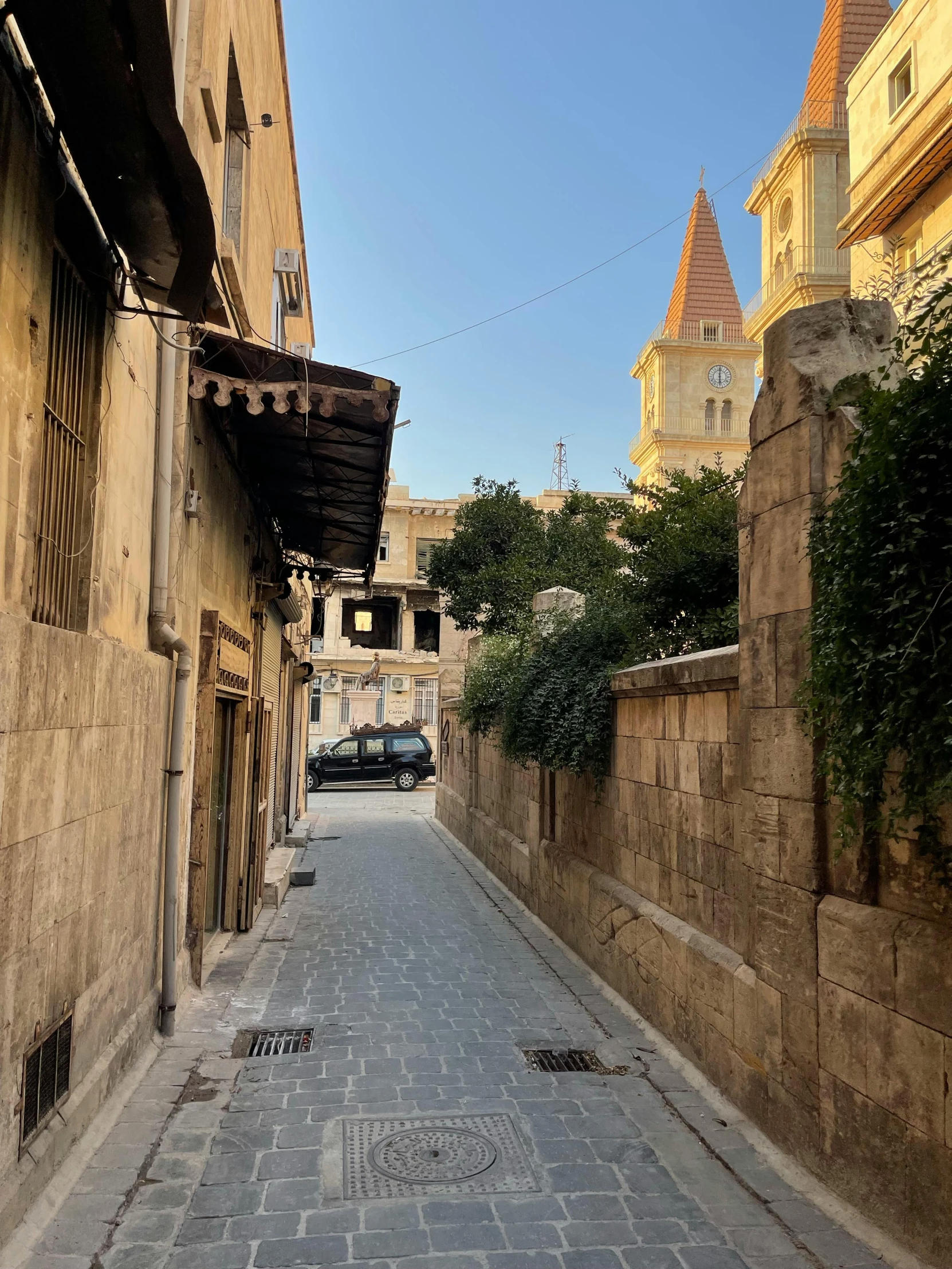 a building next to a stone pathway with cars parked on the other side