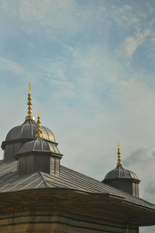 some golden metal roof tops against a cloudy blue sky