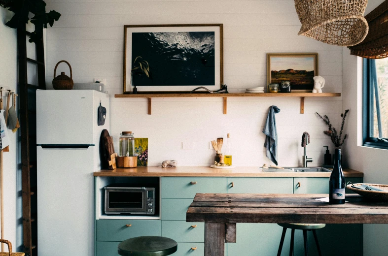 a kitchen area with a refrigerator, counter and stools