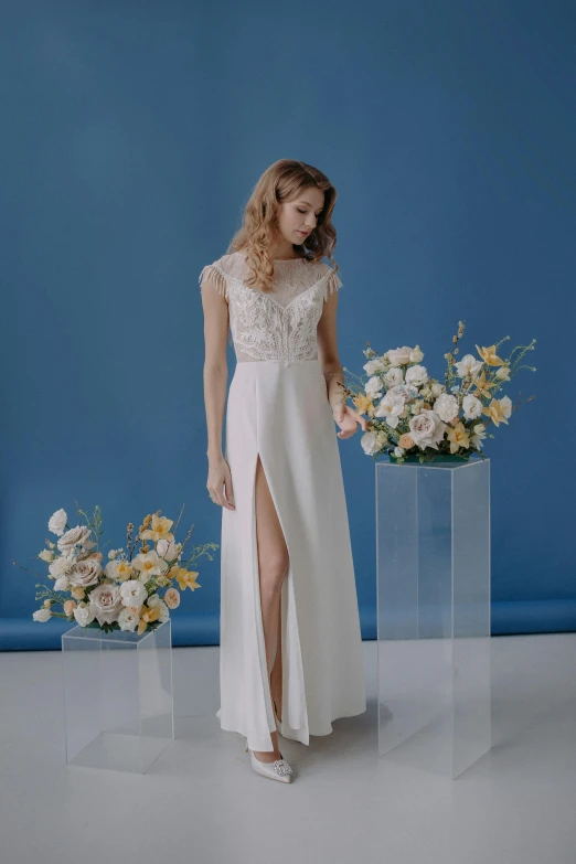 the bride is wearing a white dress and standing in front of flowers