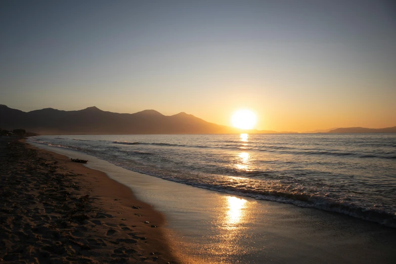 the sun is setting over the water at a beach