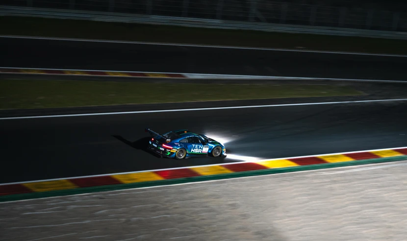 a blue car turning on the racetrack during night