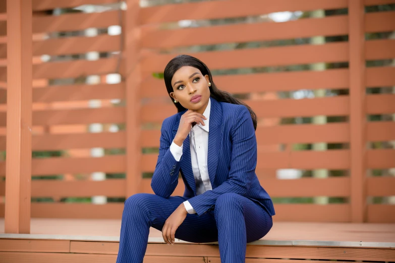 a woman sitting on the ground in a blue suit and matching heels