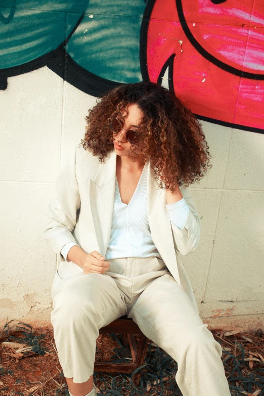 a woman sitting on a bench next to a wall