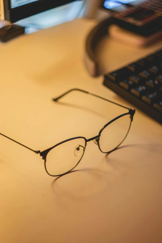 a pair of glasses resting on the desk next to a computer keyboard