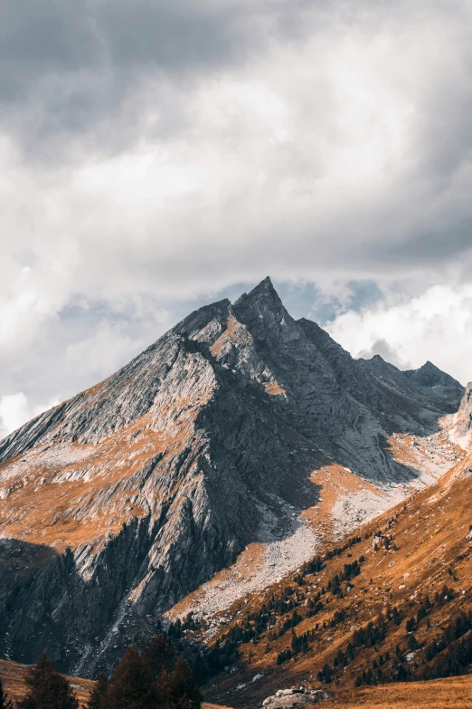 mountain peaks under stormy skies as seen from the base of the mountain