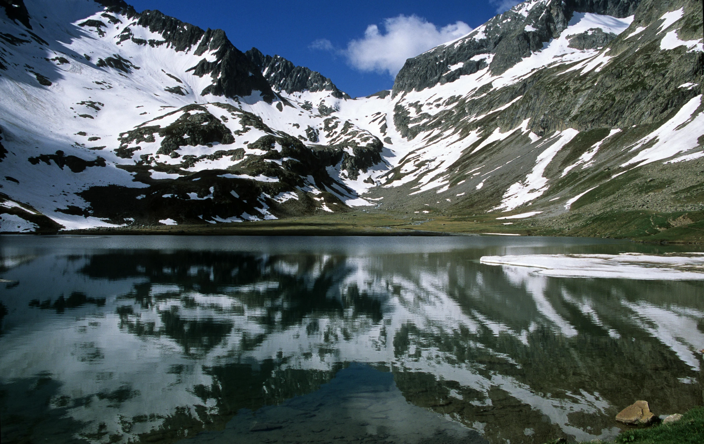 a mountain landscape with water and snow on the side