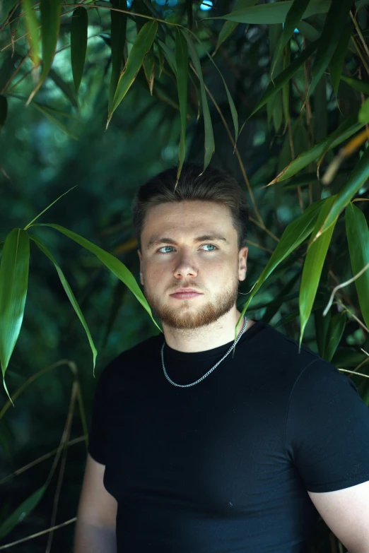 a man posing for a po with a bush in the background