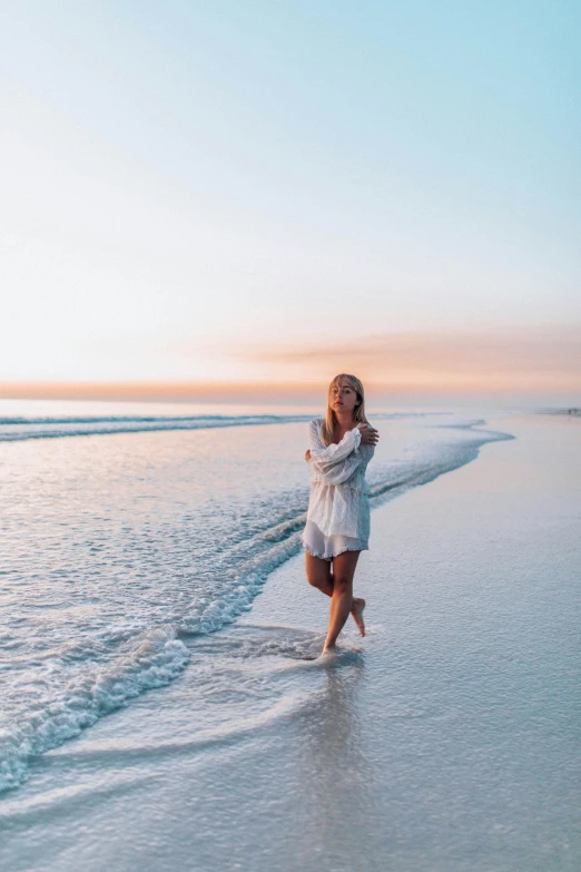 a woman walking along the beach on a clear day