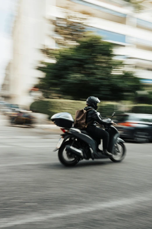 a person riding on a black motorcycle down a street