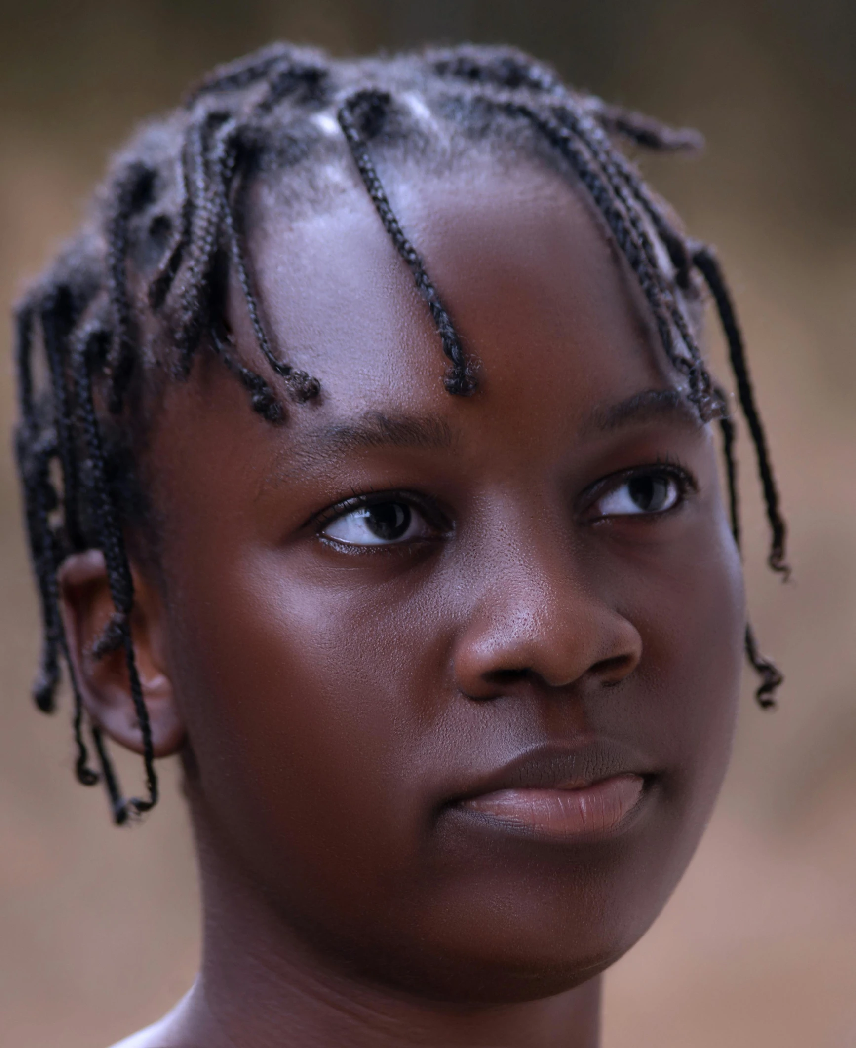 a young woman with short dreadlocks looking at the camera