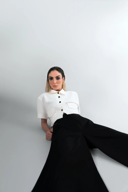 a woman in white shirt sitting next to a wall