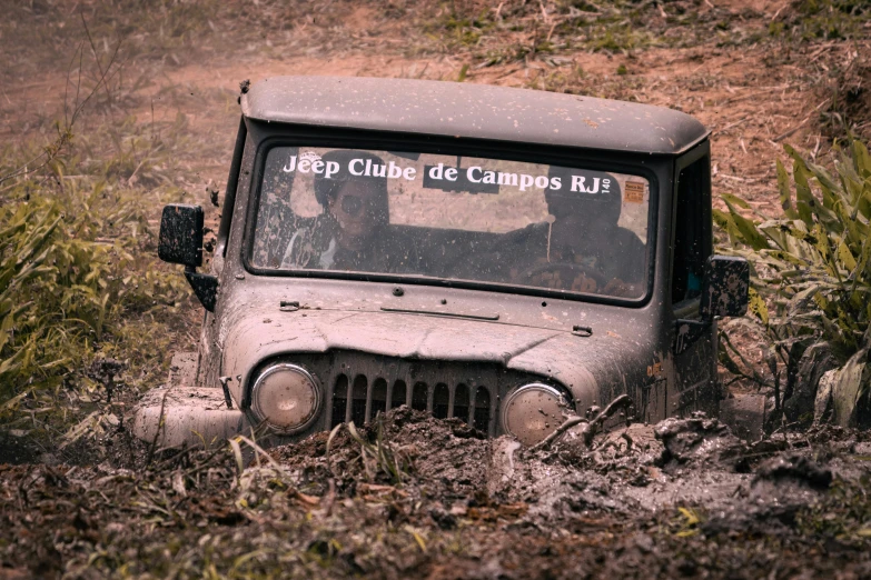 an old jeep stuck in mud on a dirt road