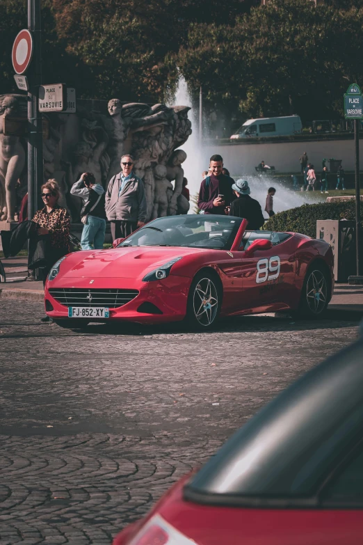 the red sports car is parked on the cobblestone