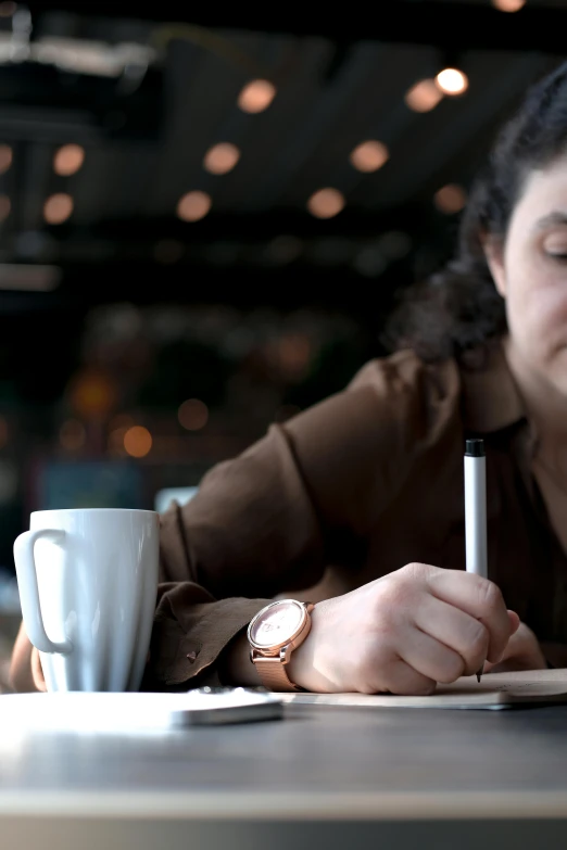 a woman is writing in her notebook with a pen and paper