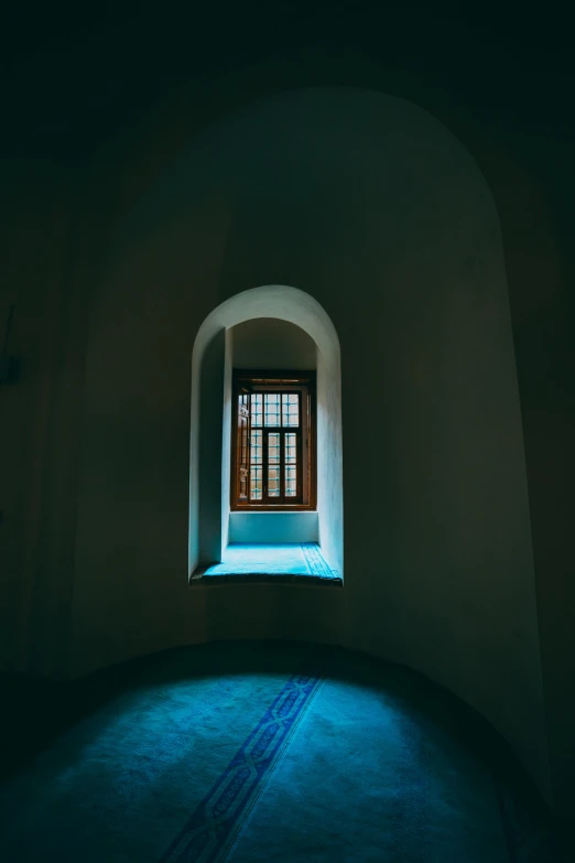 a window on an arched wall in a dark room