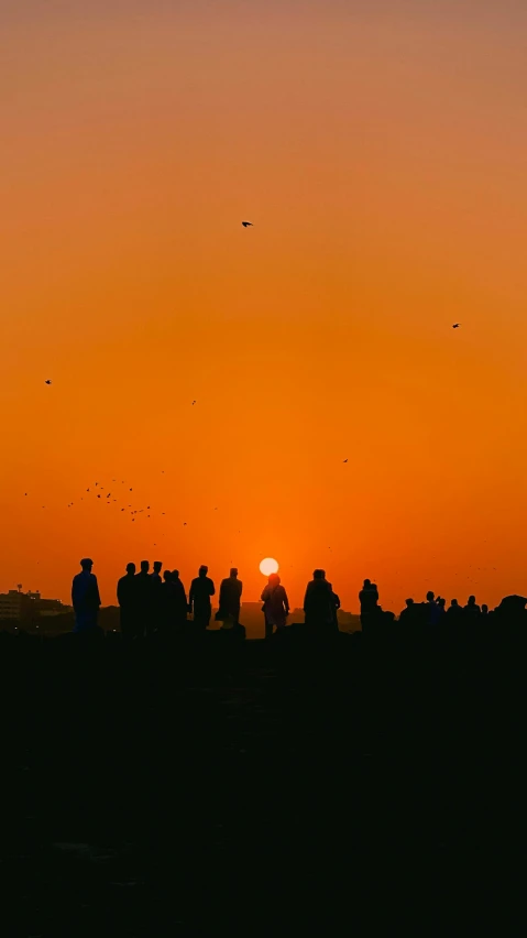 silhouettes of people watching the sun set at sunset