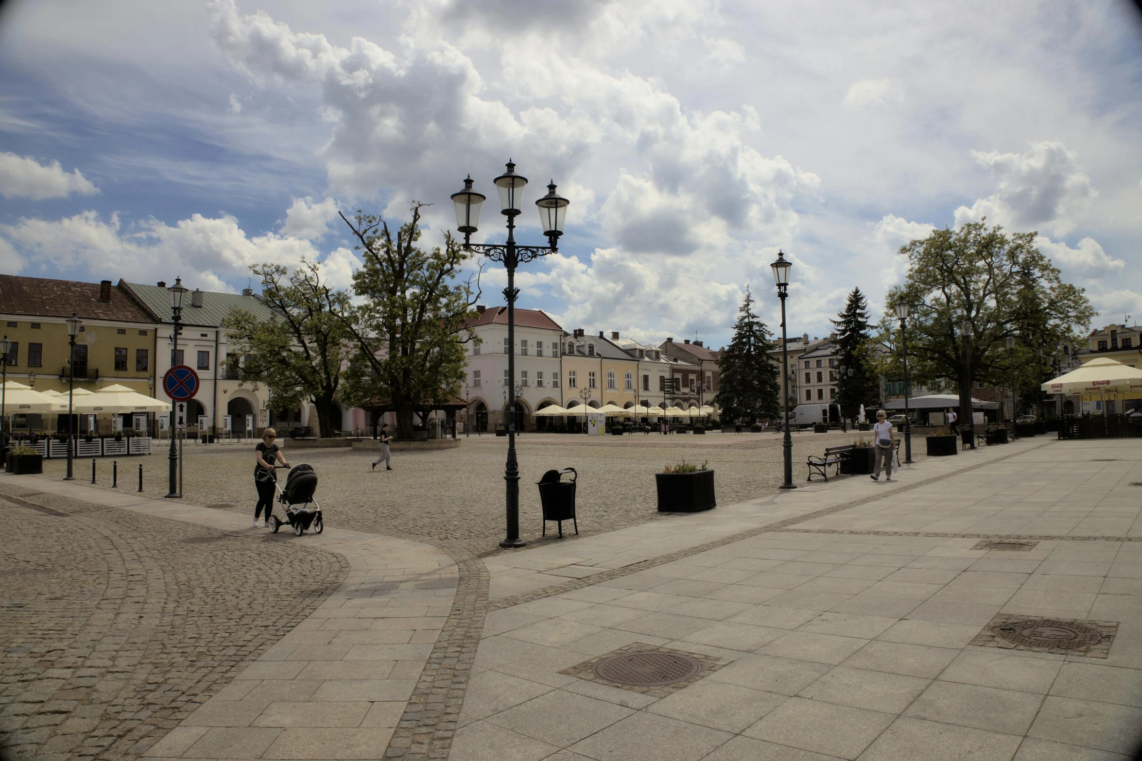 people walking around and sitting at tables on a sidewalk